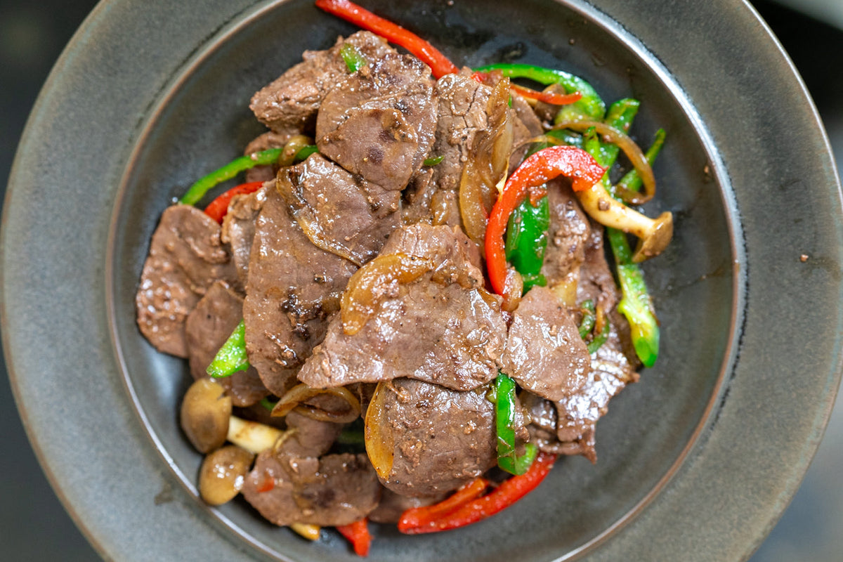 薄切り肉と赤・緑のピーマン、きのこの炒め物を真上から写したもの