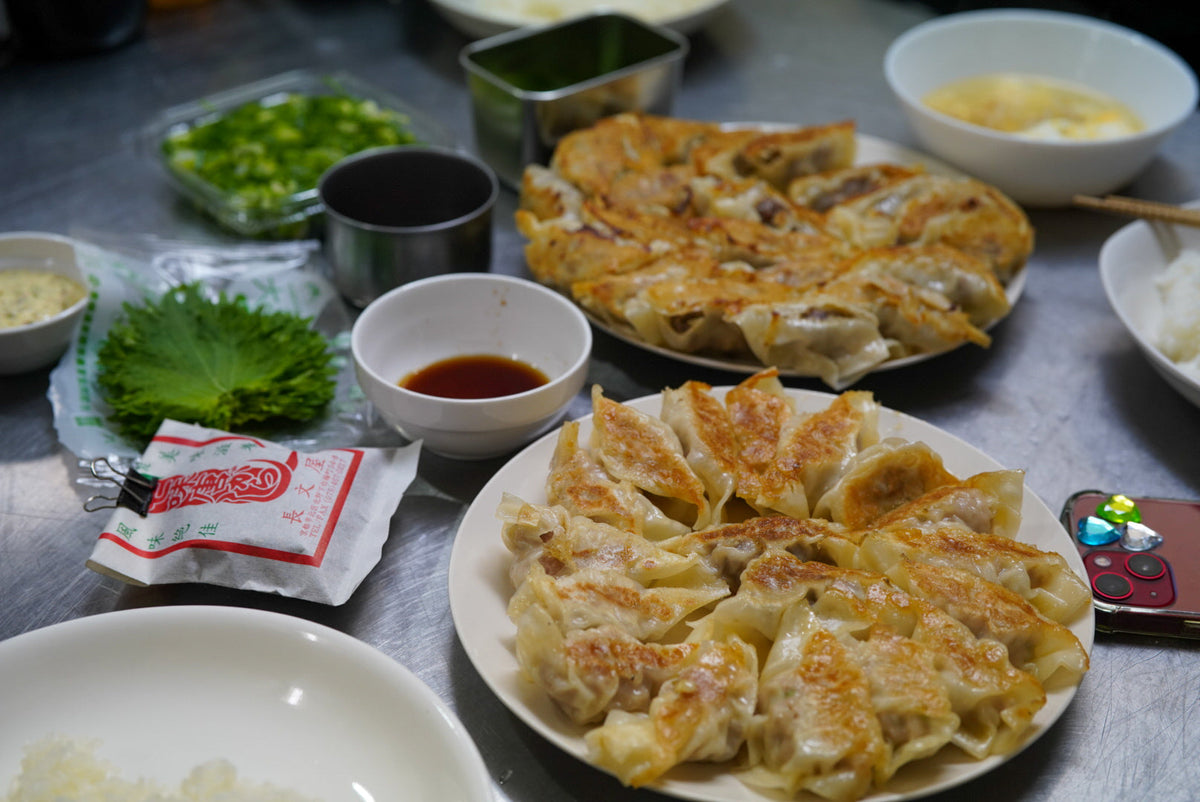 焼き餃子2皿と薬味、汁物を並べた食卓