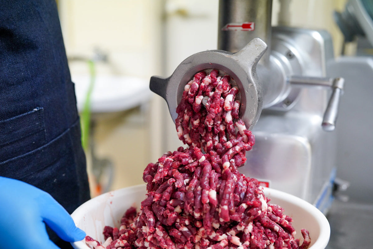 ミンサーで肉を挽いてボウルに受ける工程