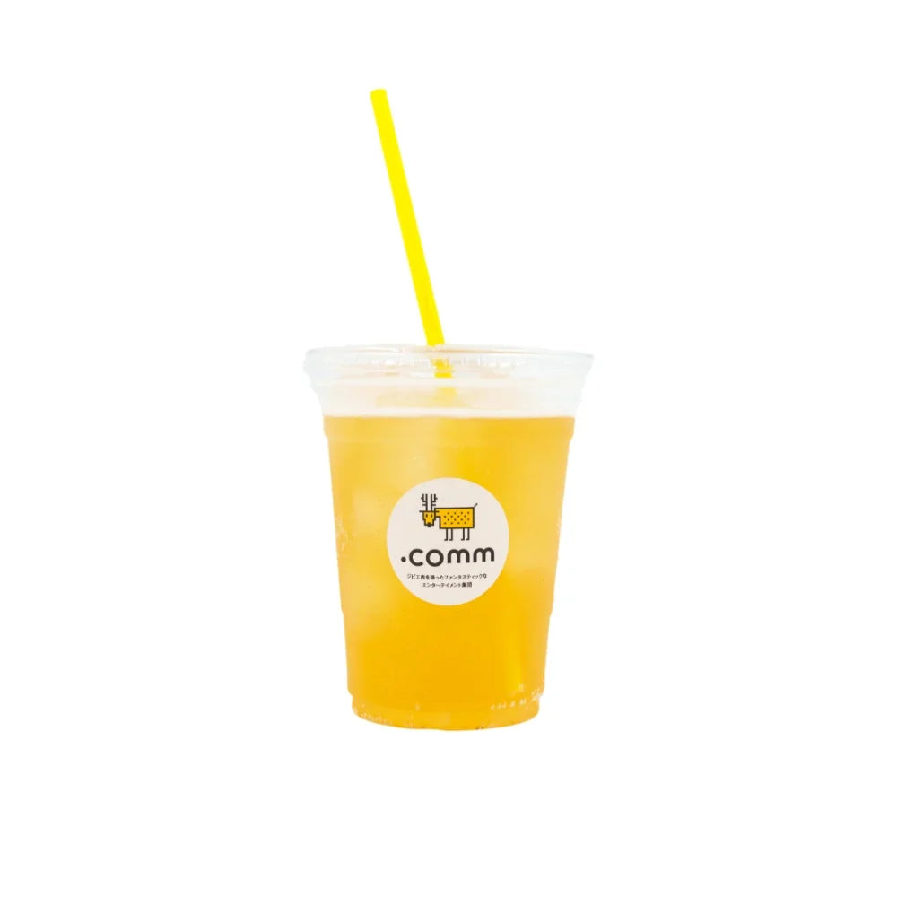 .commロゴ入りカップの黄色いドリンク